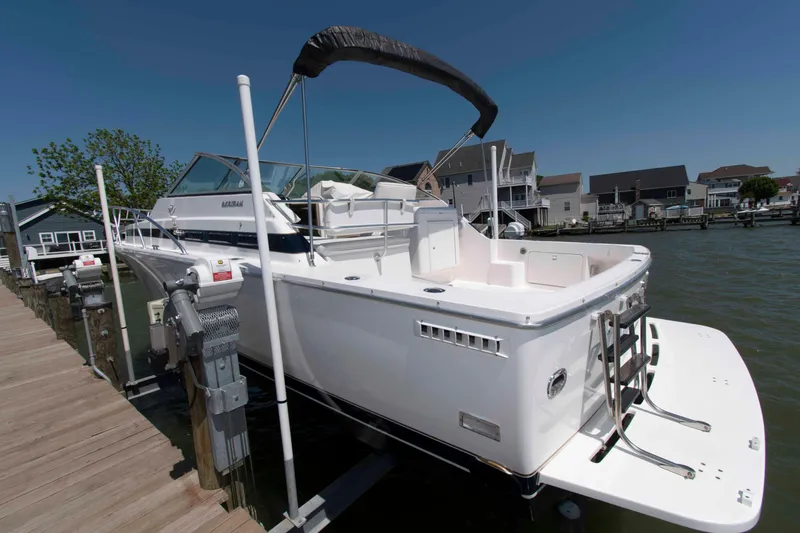 Slide: The Image of 1995 Bertram 30 Moppie boat docked by waterfront homes under clear blue sky. - 4