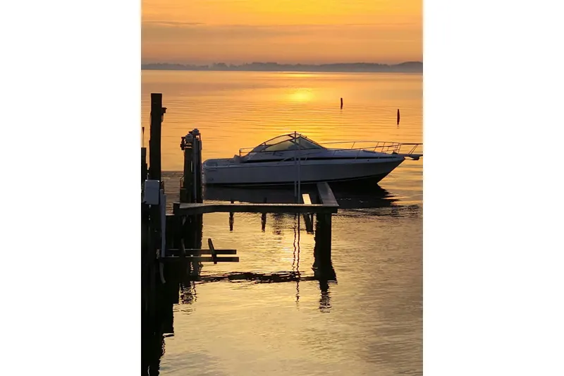Slide: The Image of 1995 Bertram 30 Moppie boat docked at sunset, reflecting on calm water. - 5
