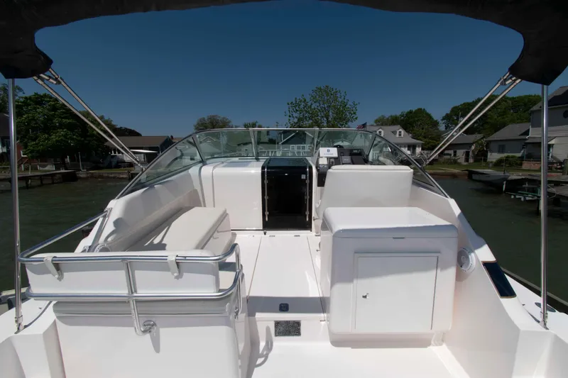 Slide: The Image of 1995 Bertram 30 Moppie boat interior with seating and helm, docked near waterfront homes. - 7
