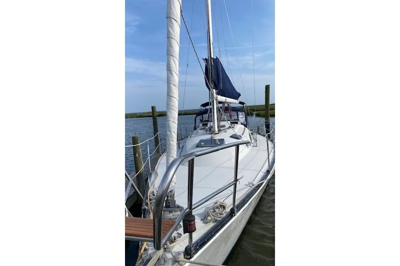 Slide: The Image of 1987 C&C Mark III sailboat docked, featuring a sleek white deck and blue sail cover. - 15