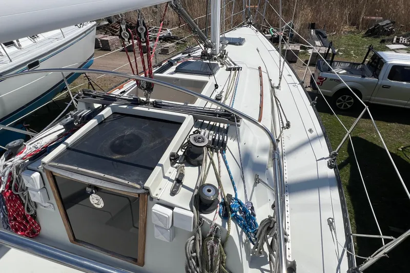 Slide: The Image of 1987 C&C Mark III sailboat deck with rigging and winches, parked near a truck. - 22