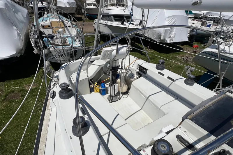 Slide: The Image of 1987 C&C Mark III sailboat cockpit with winches and steering wheel, docked among other boats. - 23