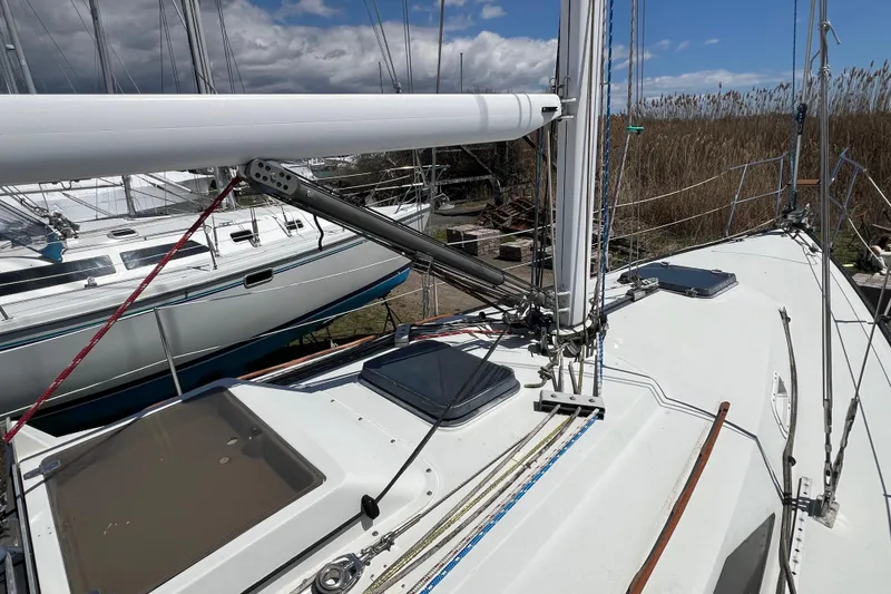 Slide: The Image of 1987 C&C Mark III sailboat deck with rigging and hatches, docked alongside another vessel. - 24