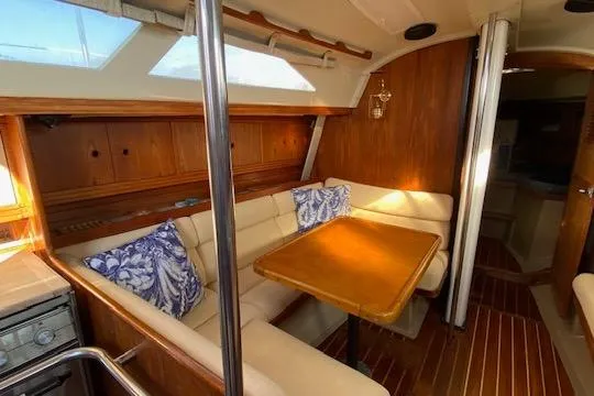 Slide: The Image of Interior of 1987 C&C Mark III sailboat with cozy dining area and wooden accents. - 3