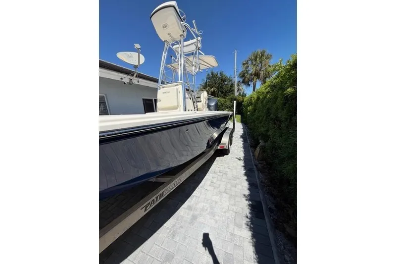 Slide: The Image of 2018 Pathfinder 2500 Hybrid boat on trailer, parked beside a house under clear blue sky. - 2