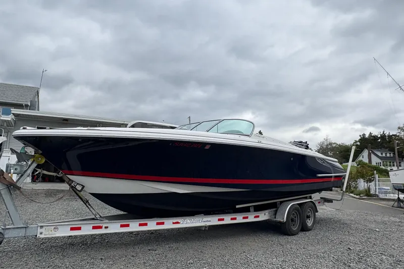 Slide: The Image of 2002 Chris-Craft Launch 28 boat on trailer, parked outdoors under cloudy sky. - 22