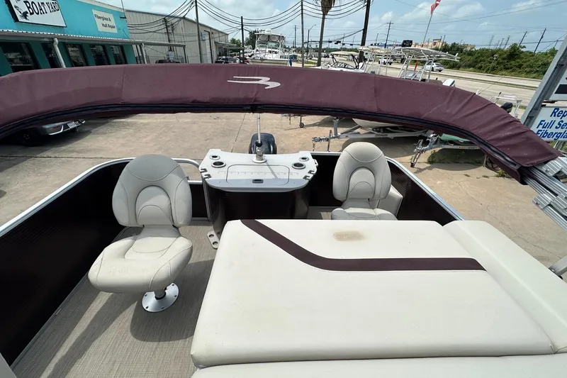 Slide: The Image of 2018 Bennington 20 SX Fish pontoon boat with seating and canopy, parked at a boatyard. - 13