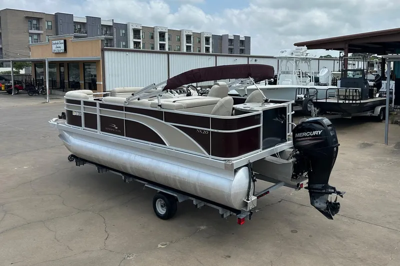 Slide: The Image of 2018 Bennington 20 SX Fish pontoon boat with Mercury outboard motor, parked on a trailer. - 3