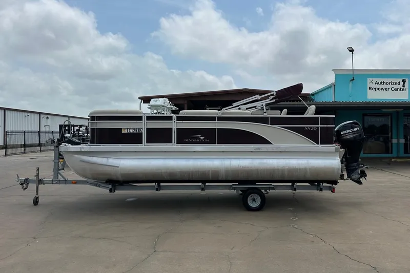 Slide: The Image of 2018 Bennington 20 SX Fish pontoon boat on trailer, parked near repower center. - 9