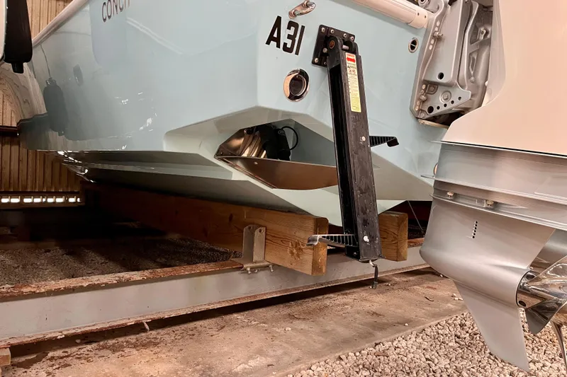 Slide: The Image of 2023 Conch 30 boat on wooden supports in a storage facility. - 21