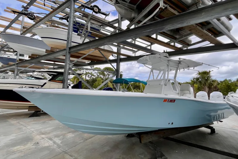 Slide: The Image of 2023 Conch 30 boat in storage, light blue hull, triple Mercury engines, outdoor setting. - 25