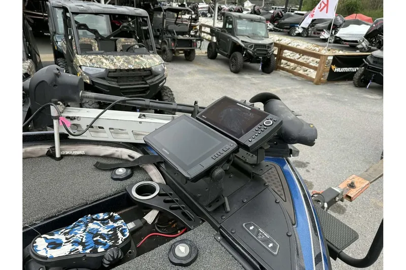 Slide: The Image of Nitro Z20 Pro 2022 boat dashboard with electronic displays and controls, parked near off-road vehicles. - 6