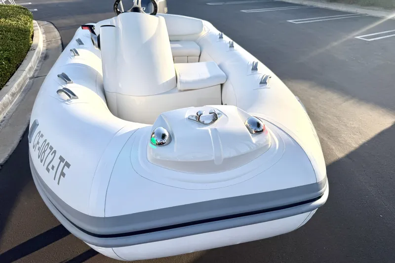 Slide: The Image of 2019 Brig Eagle 340 inflatable boat parked on asphalt, showcasing sleek design and white exterior. - 10