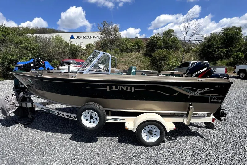 The Image of 2000 Lund 1700 Pro Sport boat on trailer, parked outdoors under a blue sky. - 0