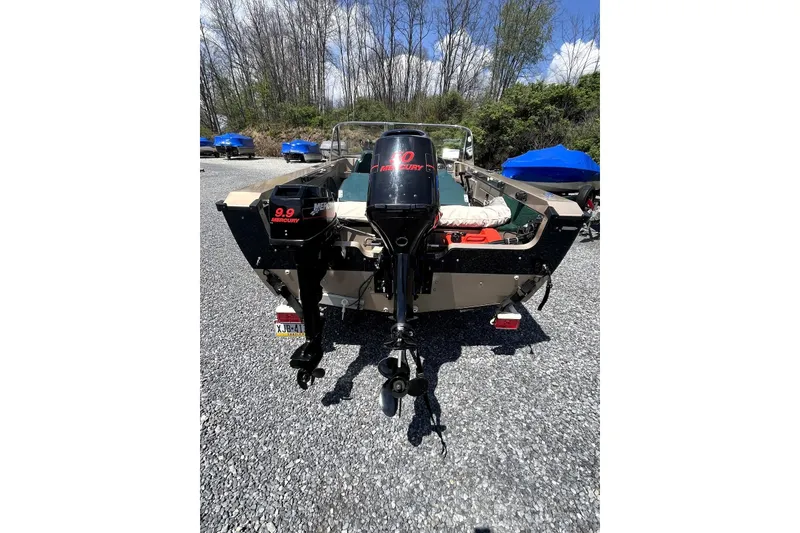Slide: The Image of 2000 Lund 1700 Pro Sport boat with dual Mercury 9.9 outboard motors, parked outdoors. - 3