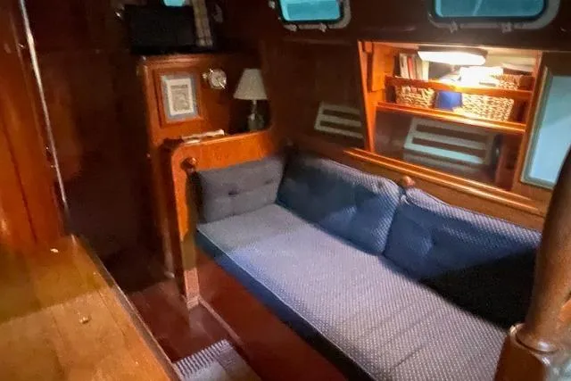 Slide: The Image of Cozy interior of 1984 Endeavour 35 sailboat with blue cushioned seating and wooden accents. - 27