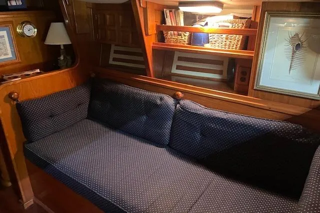 Slide: The Image of Cozy interior of 1984 Endeavour 35 yacht with blue cushioned seating and wooden shelving. - 28