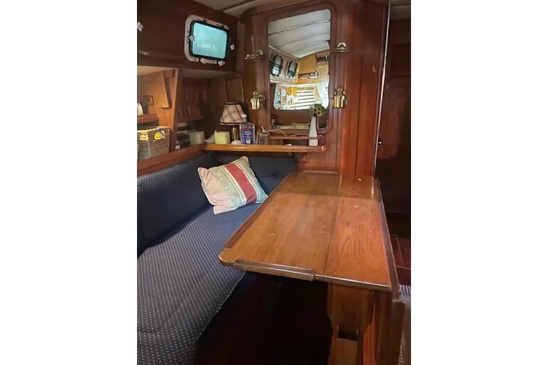 Slide: The Image of Cozy interior of 1984 Endeavour 35 sailboat with wooden table and cushioned seating. - 31