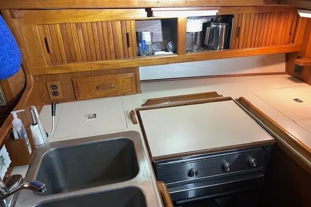 Slide: The Image of 1984 Endeavour 35 yacht kitchen with wooden cabinets, dual sink, and stove. - 34