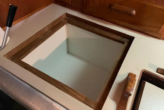 Slide: The Image of Open storage compartment on 1984 Endeavour 35 boat, featuring wooden trim and adjacent cabinetry. - 37