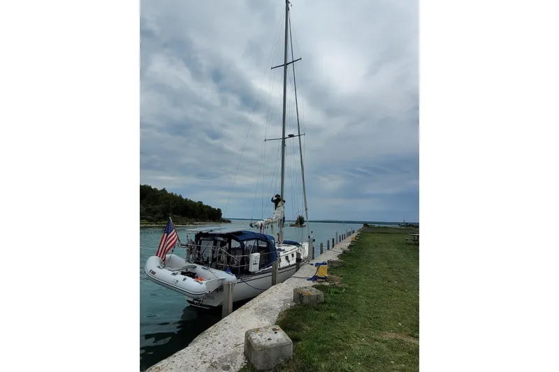 Slide: The Image of 1984 Endeavour 35 sailboat docked by a grassy shoreline under a cloudy sky. - 5