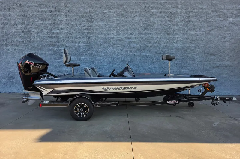 The Image of 2026 Phoenix 818 Pro fishing boat on trailer, side view against gray wall. - 2