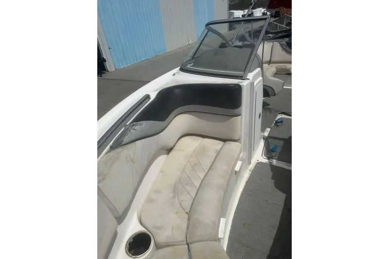 Slide: The Image of 2008 Yamaha Boats SX230 interior with worn seating and windshield, docked near a blue building. - 12