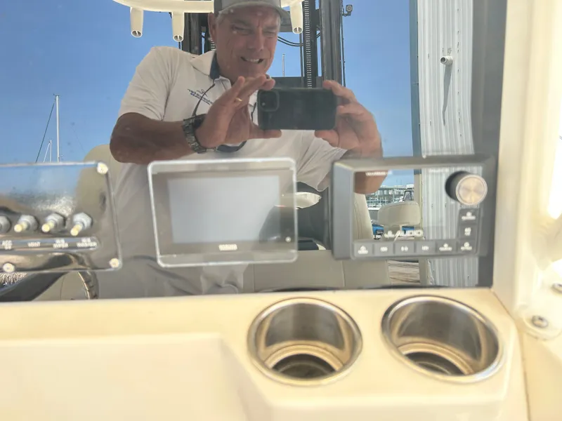 Slide: The Image of Man taking a photo in the cockpit of a Cobia 262 Center Console boat. - 23
