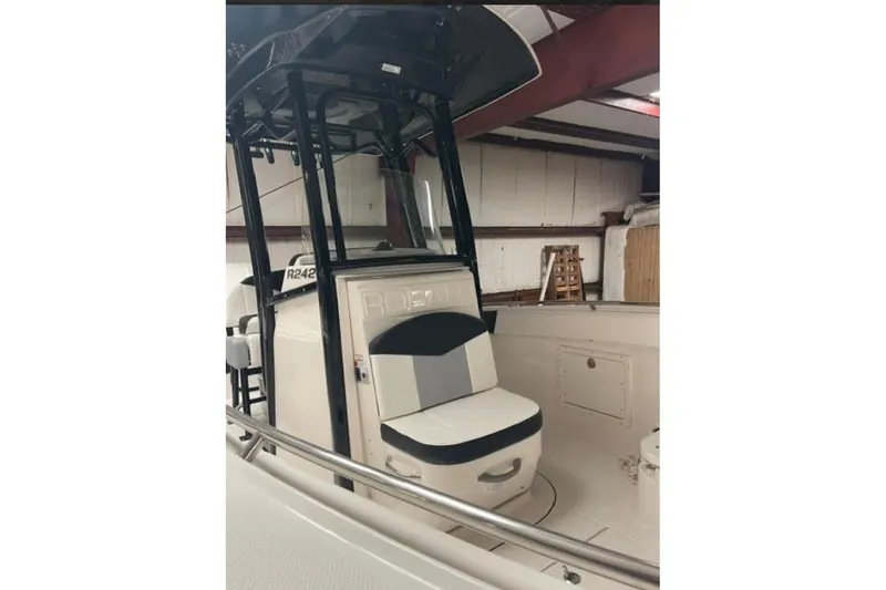 Slide: The Image of 2023 Robalo R242 Explorer boat interior with seating and console in a warehouse setting. - 6