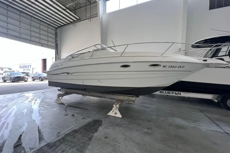 The Image of 2002 Larson Cabrio 254 boat in a garage, elevated on stands. - 1