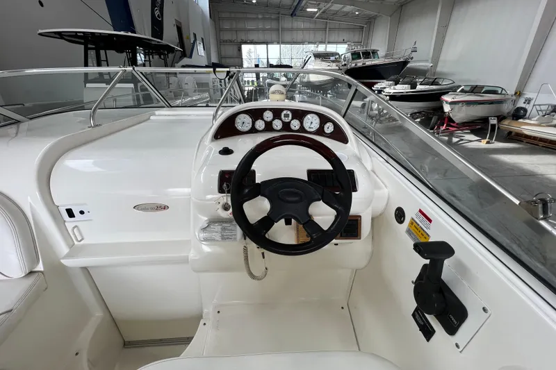 Slide: The Image of 2002 Larson Cabrio 254 boat cockpit with steering wheel and instrument panel in a showroom. - 11