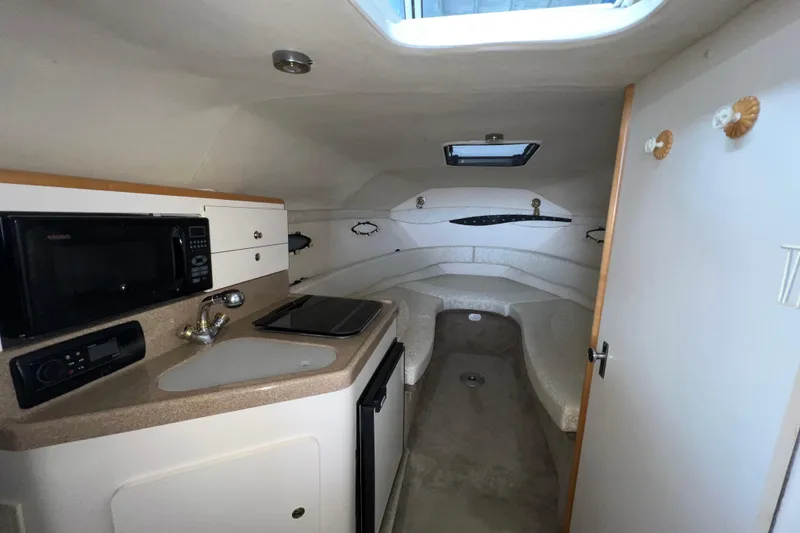 Slide: The Image of 2002 Larson Cabrio 254 cabin interior with kitchenette, sink, and seating area. - 13