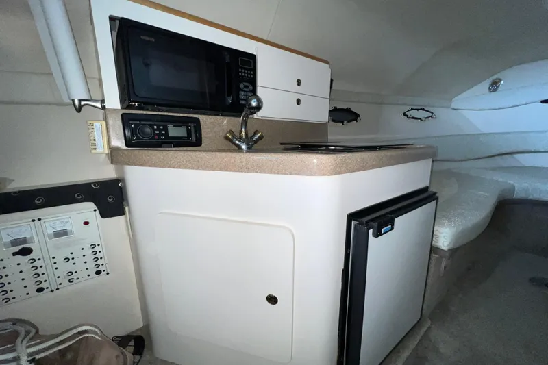 Slide: The Image of Interior of 2002 Larson Cabrio 254 boat featuring kitchenette with microwave and mini-fridge. - 14