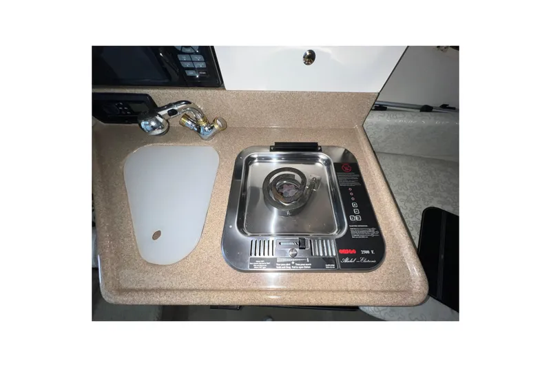 Slide: The Image of 2002 Larson Cabrio 254 boat kitchenette with sink and stove. - 18