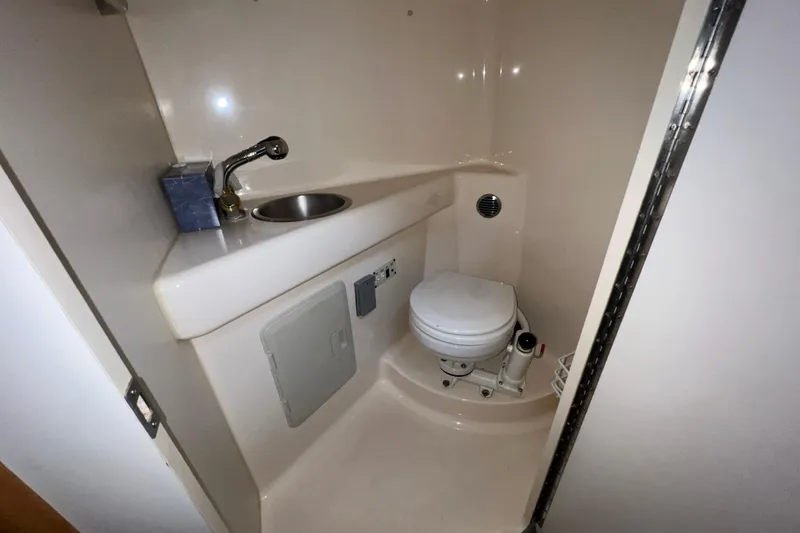 Slide: The Image of Compact bathroom in a 2002 Larson Cabrio 254 boat, featuring a sink and toilet. - 19