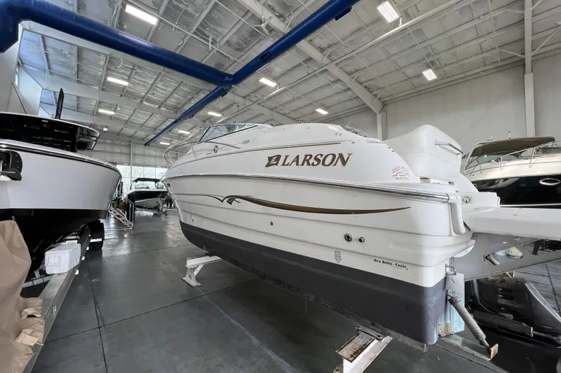 Slide: The Image of 2002 Larson Cabrio 254 boat displayed in a spacious indoor showroom. - 3