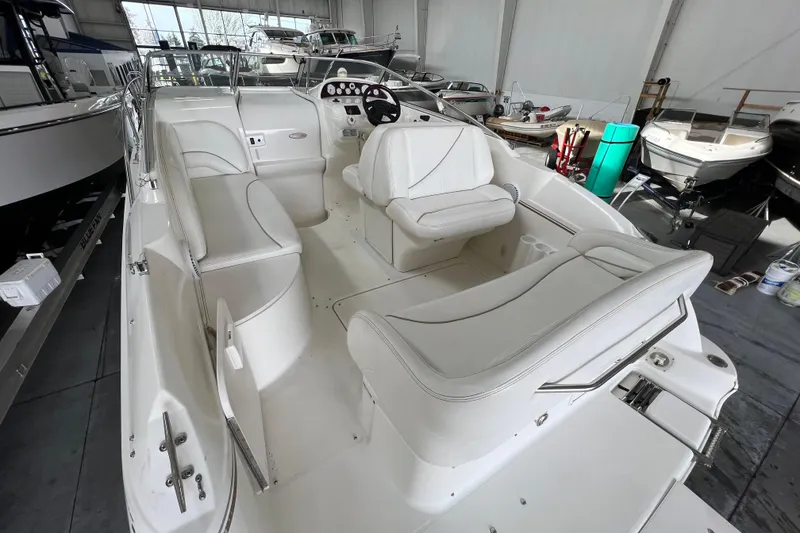 Slide: The Image of 2002 Larson Cabrio 254 boat interior with white seating in a showroom. - 7