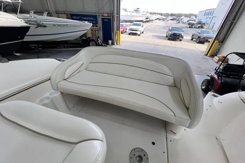 Slide: The Image of 2002 Larson Cabrio 254 boat interior with white seating in a marina setting. - 9