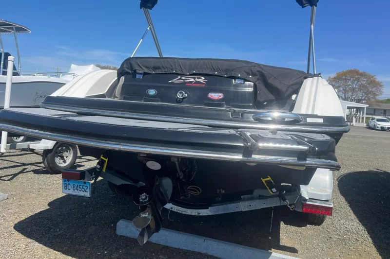 Slide: The Image of 2013 Larson LSR 2300 I/O boat, rear view, parked on a trailer in a sunny outdoor setting. - 4