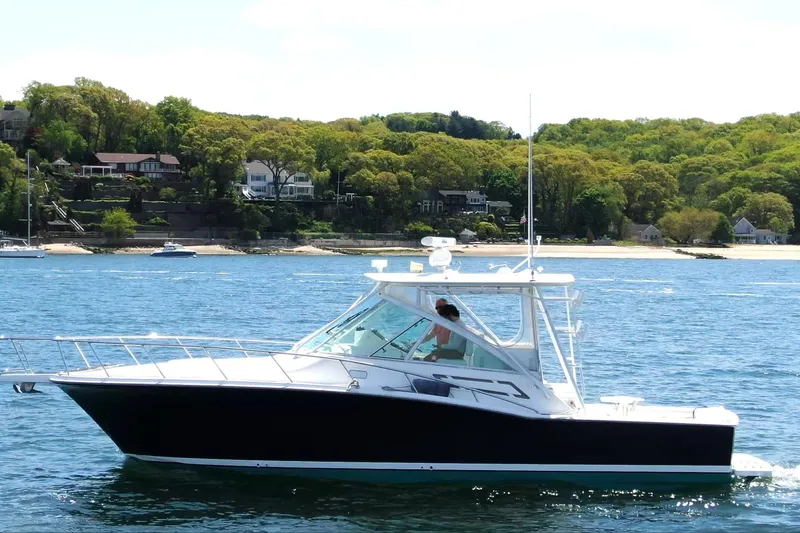 The Image of 2008 Cabo 32 Express boat cruising on a scenic lake with lush green shoreline. - 0