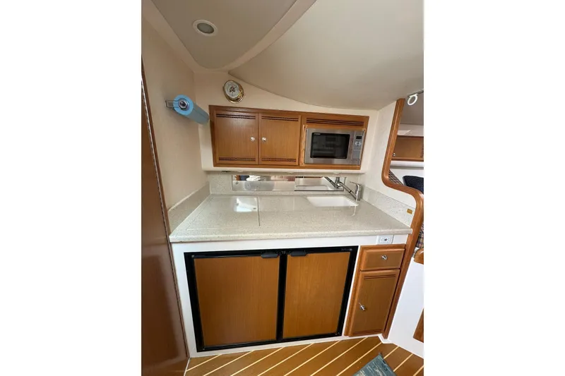 Slide: The Image of Compact kitchen area in a 2008 Cabo 32 Express boat with wooden cabinets and appliances. - 28