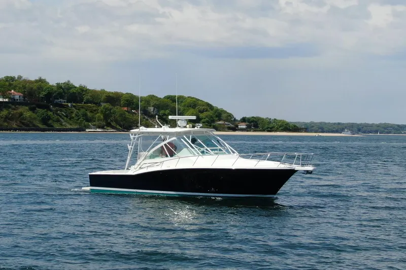 Slide: The Image of 2008 Cabo 32 Express boat cruising on a scenic coastal waterway. - 4