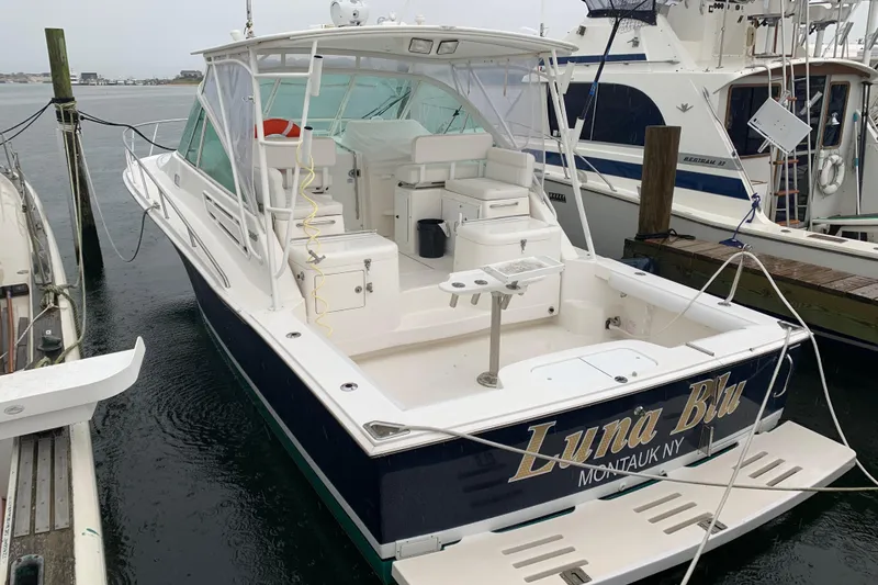 Slide: The Image of 2008 Cabo 32 Express boat docked, featuring spacious deck and seating area. - 5