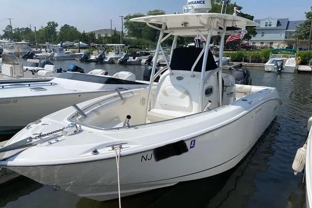 Slide: The Image of 2007 Boston Whaler 240 Outrage boat docked in a marina, showcasing sleek design and spacious deck. - 2