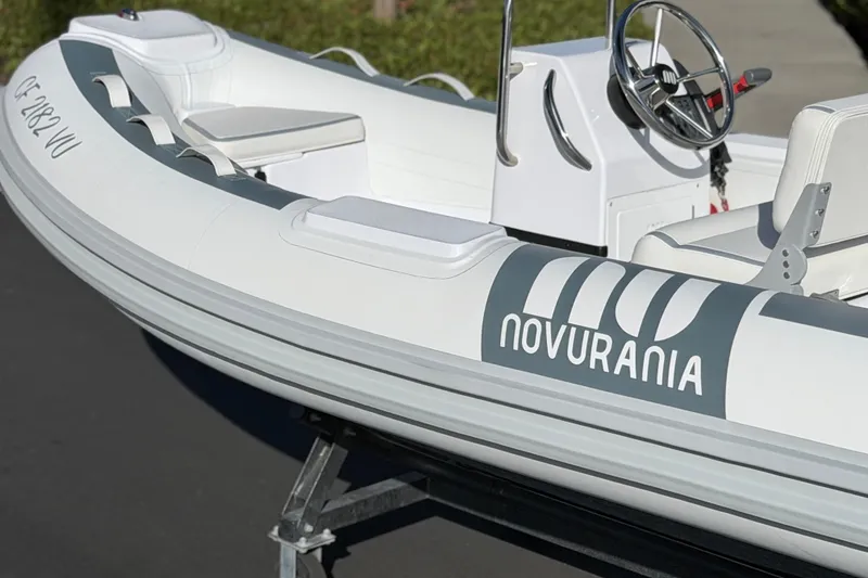 Slide: The Image of 2021 Novurania Deluxe 335 inflatable boat with steering wheel and seating, displayed on a trailer. - 18