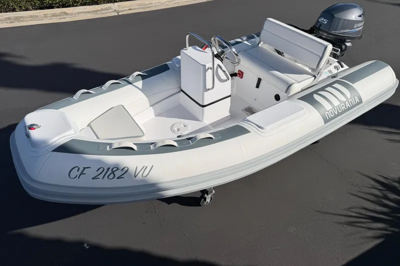 Slide: The Image of 2021 Novurania Deluxe 335 inflatable boat with Yamaha motor, parked on pavement. - 21