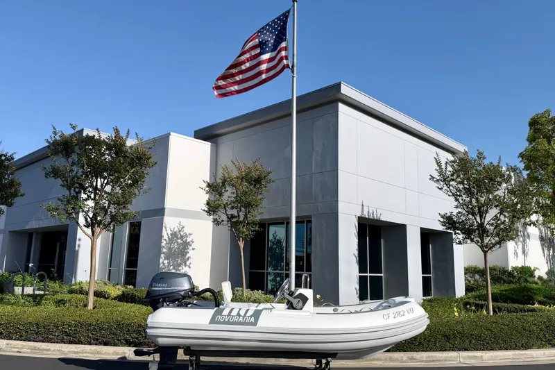 Slide: The Image of Novurania Deluxe 335 boat, 2021 model, displayed outside modern building with American flag. - 23