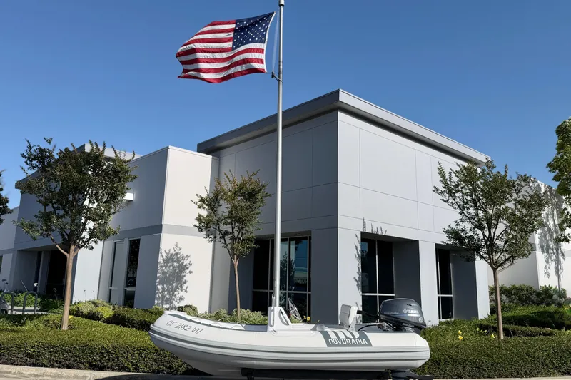 Slide: The Image of Novurania Deluxe 335 boat, 2021 model, displayed outside modern building with American flag. - 8