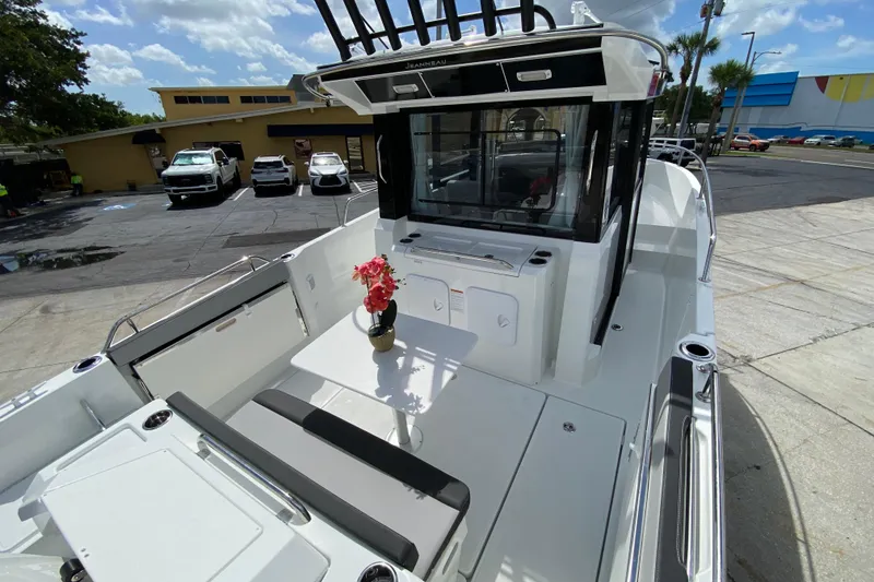 Slide: The Image of 2026 Jeanneau NC Sport 795 Series 2 boat with outdoor seating and table, parked in a lot. - 6