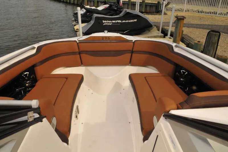 Slide: The Image of 2024 Yamaha Boats 275SDX interior with brown seating, docked near water. - 28